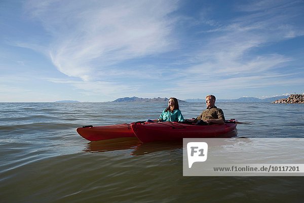 Young couple in kayaks on water  eyes closed looking away  Great Salt Lake  Utah  USA