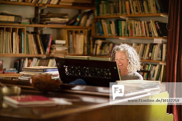 Reife Frau lächelt beim Klavierspielen im Wohnzimmer