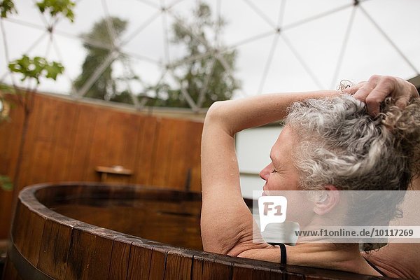 Reife Frau mit Händen im Haar im Whirlpool beim Öko-Retreat