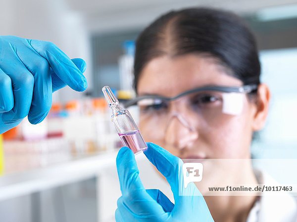 Wissenschaftlerin beim Testen von Medikamentenampulle im Labor