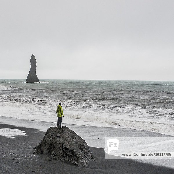Young male tourist looking out to sea from rock formation  Reynisfjara  Iceland