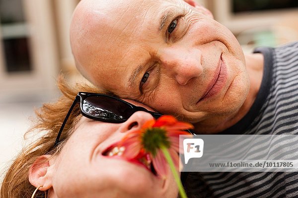 Close up portrait of smiling couple with red flower
