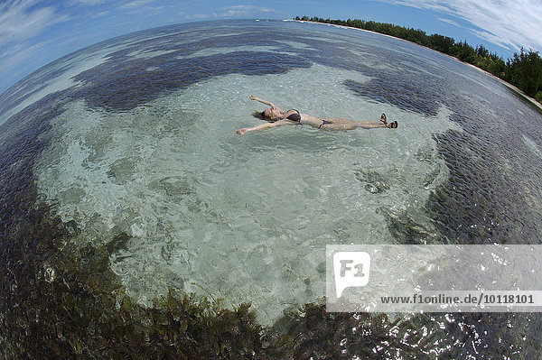 Eine junge Frau liegt im Wasser auf dem Rücken  Denis Island  Seychellen  Afrika