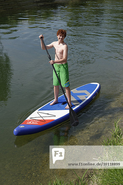 Boy on a stand up board  stand-up paddling  on the Loisach canal  Upper Bavaria  Bavaria  Germany  Europe