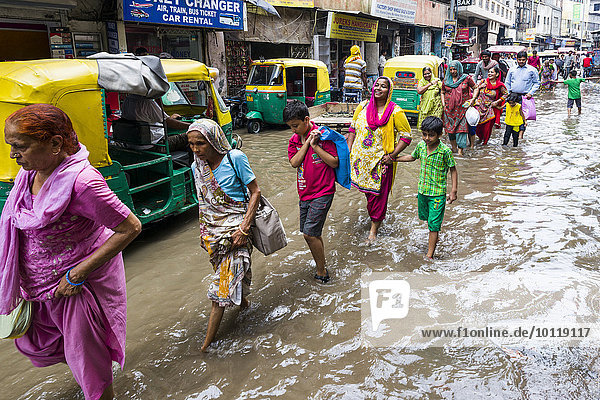 Menschen gehen und Fahrrad-Rikschas fahren durch die nach einem heftigen Monsunregenfall überfluteten Straßen der Vorstadt Paharganj  Neu-Delhi  Delhi  Indien  Asien