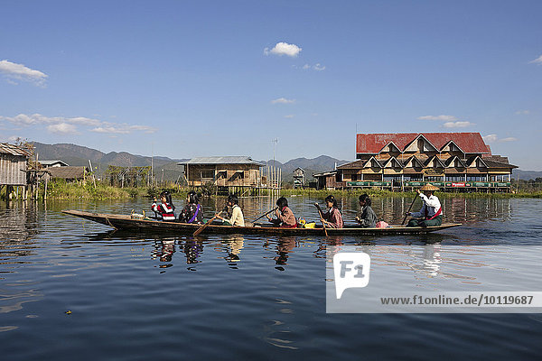Local women in a wooden boat paddling on Inle Lake  stilt houses behind  Inle Lake  Shan State  Myanmar  Asia