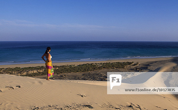 Woman standing on a sand dune overlooking the Playas de Sotavento beach  Fuerteventura  Canary Islands  Spain  Europe