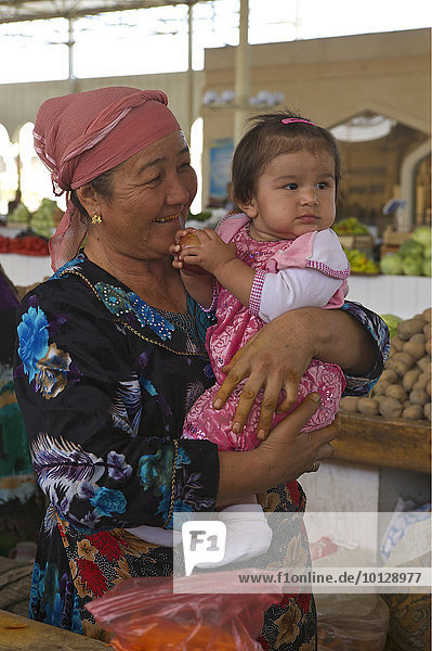 Frau hält ein kleines Mädchen auf dem Arm  auf dem Basar  Buchara  Usbekistan  Asien