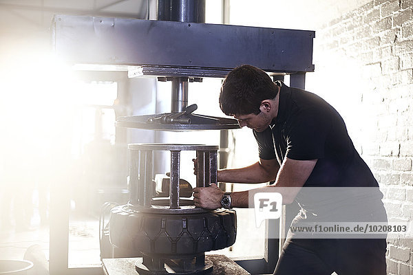 Mechaniker mit Reifenmontiermaschine in der Kfz-Werkstatt
