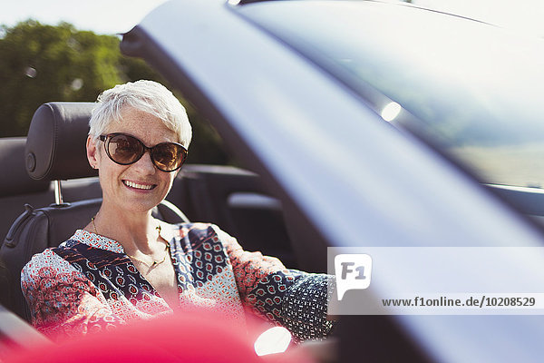 Portrait lächelnde Seniorin mit Sonnenbrille im Cabriolet