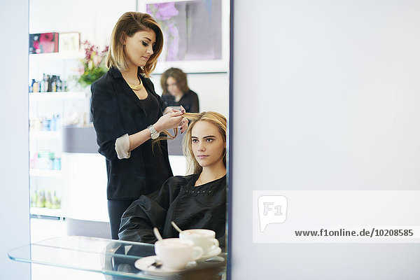 Hairdresser curling customer’s hair in salon
