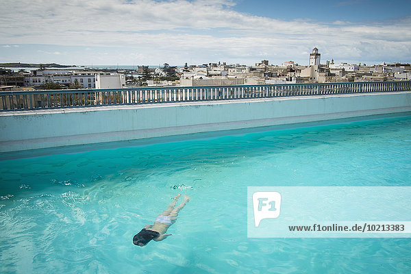 Caucasian woman swimming in urban rooftop pool