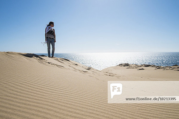 Caucasian woman standing on sand dune near ocean