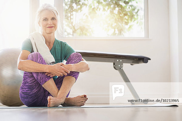 Older Caucasian woman sitting on gym floor