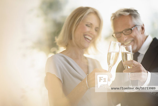Smiling older Caucasian couple toasting with champagne