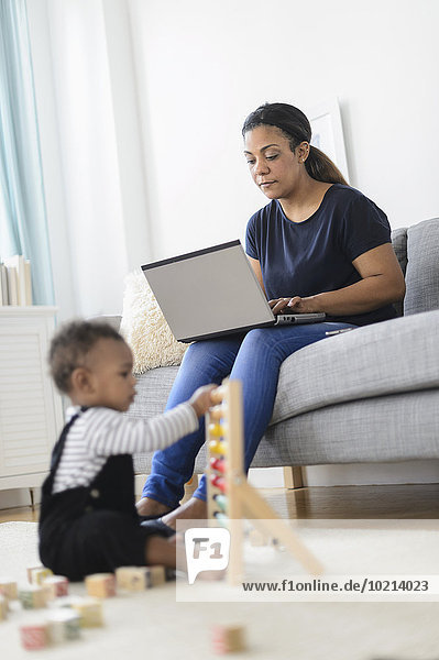 Mixed race mother and baby son relaxing in living room