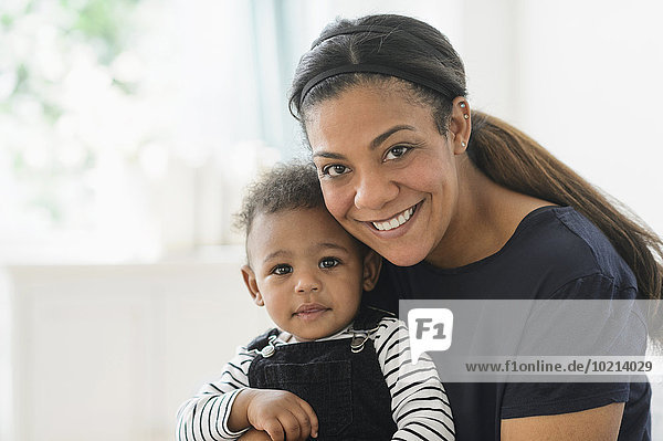 Mixed race mother holding baby son in living room