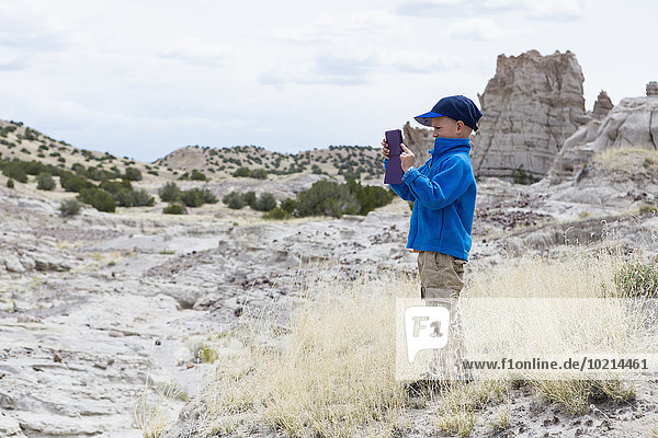 Boy photographing rock formations in desert landscape