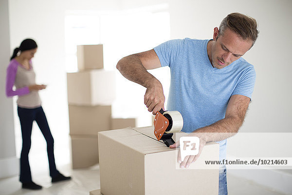 Man taping cardboard box to move