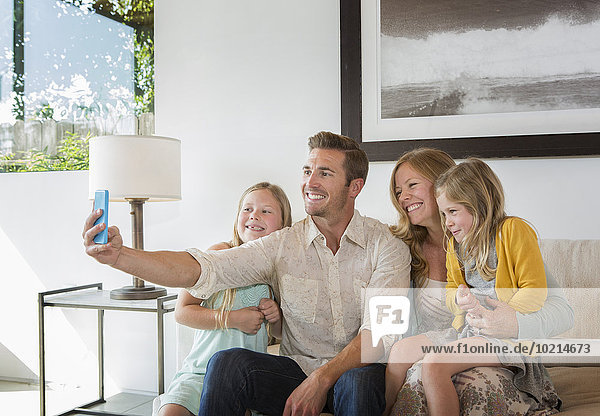 Caucasian family taking selfie on sofa