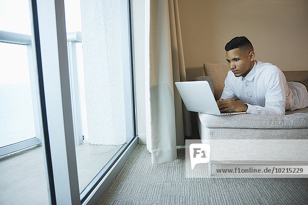 Black businessman using laptop in hotel room