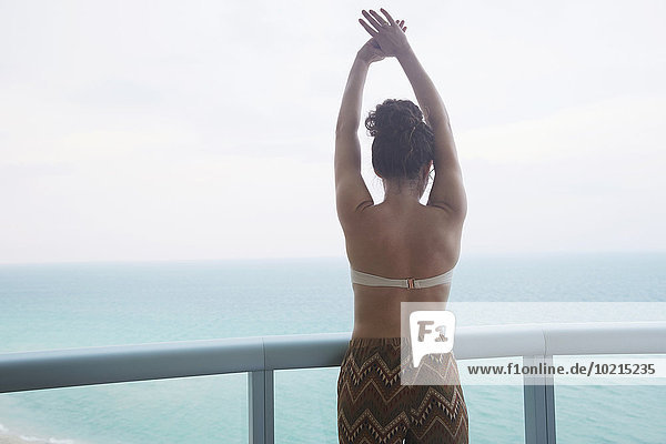 Mixed race woman overlooking ocean from balcony