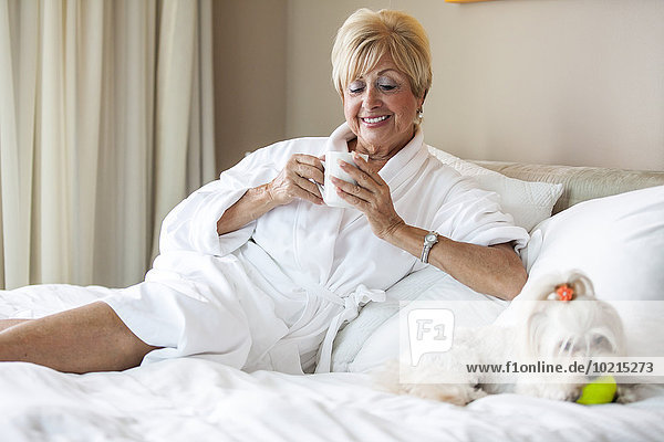 Older Caucasian woman and dog relaxing on bed