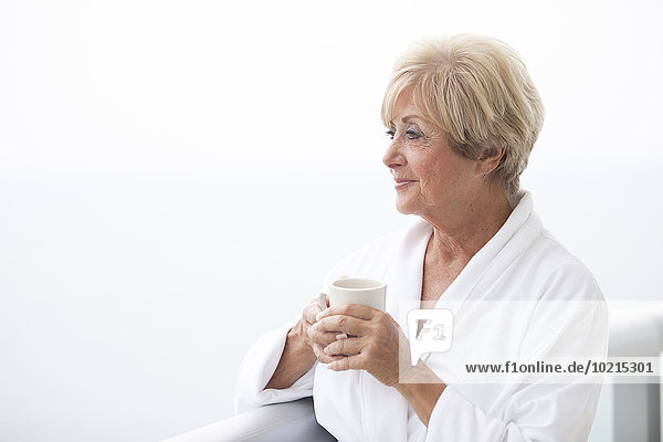 Older Caucasian woman drinking coffee on balcony
