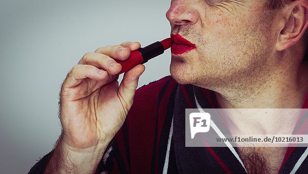 Caucasian man applying lipstick