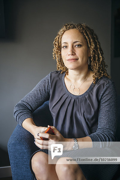 Mixed race businesswoman smiling in armchair