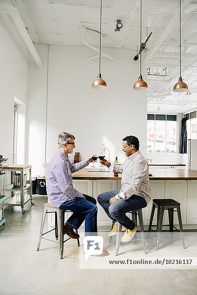 Gay couple toasting with wine at counter