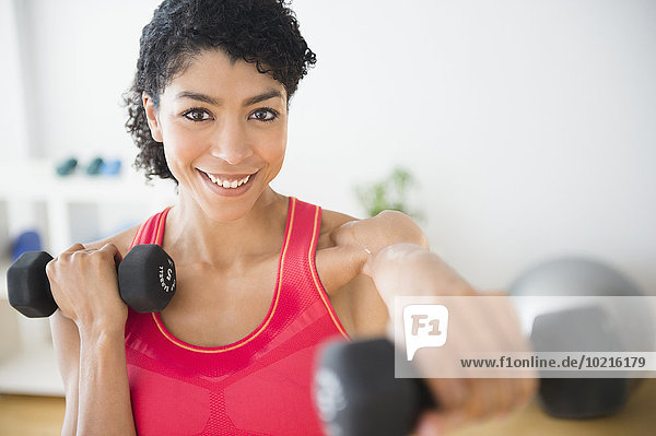 Mixed race woman lifting weights in gym