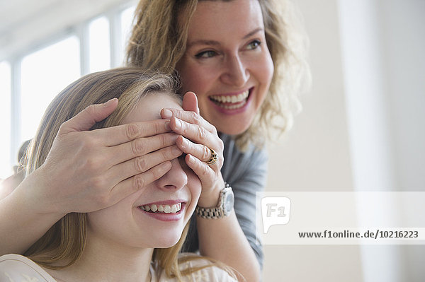 Caucasian mother covering eyes of daughter