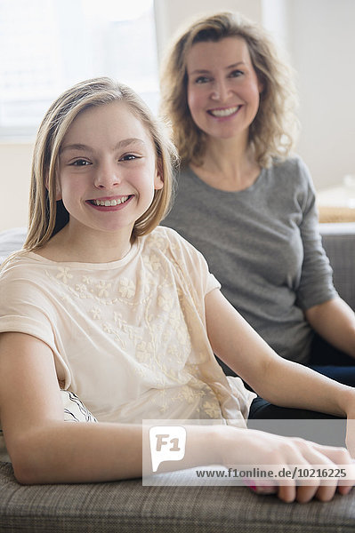 Caucasian mother and daughter smiling on sofa