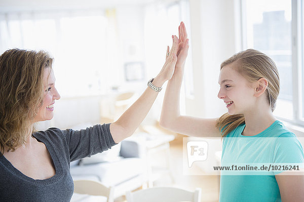 Caucasian mother and daughter high fiving in living room