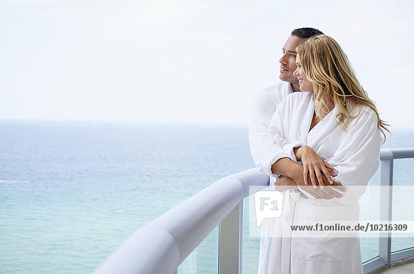 Couple hugging on balcony over ocean