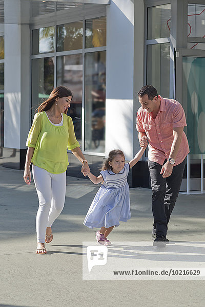 Hispanic family holding hands on sidewalk