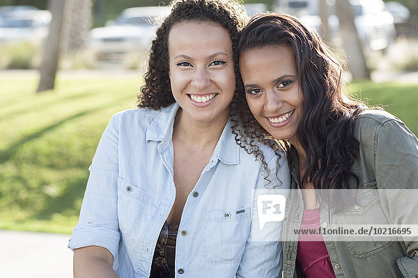 Close up of smiling women hugging in park