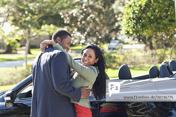 Couple hugging near convertible