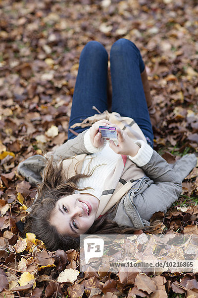 Hispanic girl laying in autumn leaves