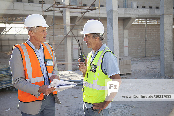Caucasian architect and construction worker talking at construction site