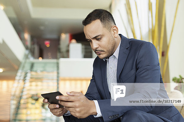 Hispanic businessman using digital tablet in hotel lobby