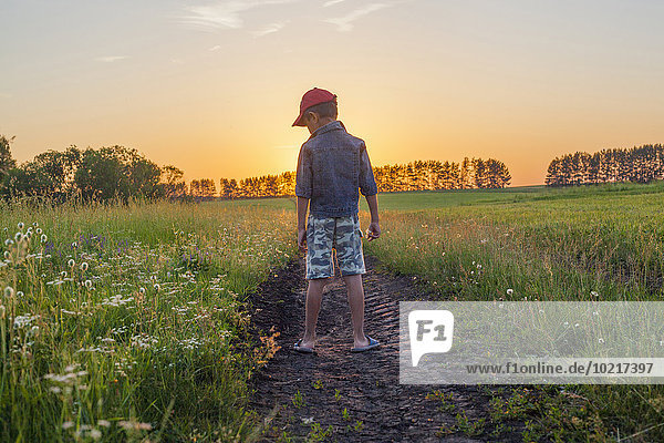 Mari boy standing in tire tracks in rural field