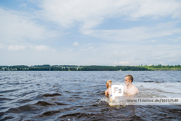 Caucasian father and son swimming in lake