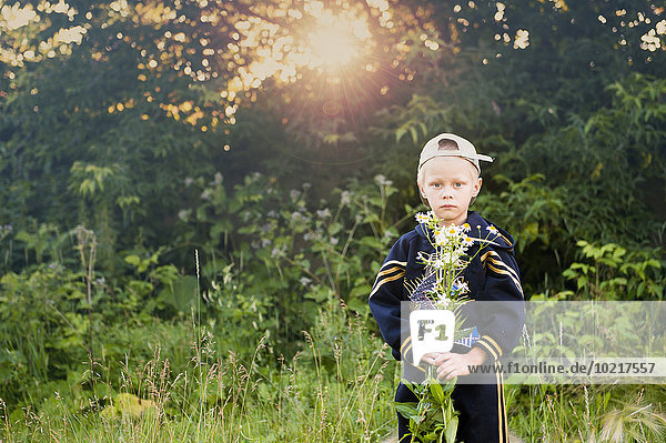 Caucasian boy picking flowers in rural field