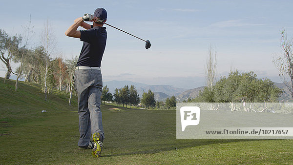 Caucasian man teeing off on golf course