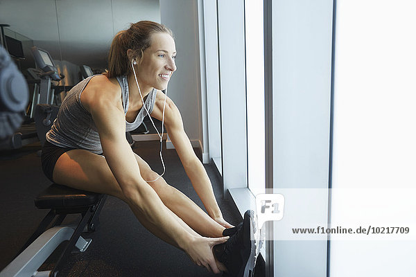 Smiling woman stretching in gym