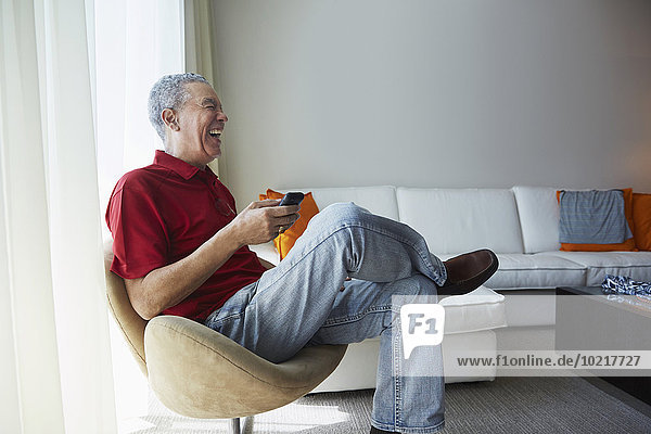 Older Black man using cell phone in living room