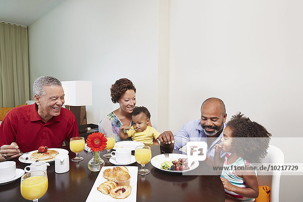 Multi-generation family eating breakfast at table
