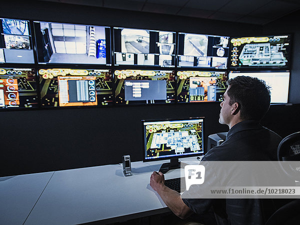 Hispanic security guard watching monitors in control room